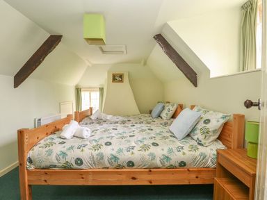 A bedroom with two single beds with floral bedding and rolled towels at Thatch Cottage in Buckland Newton