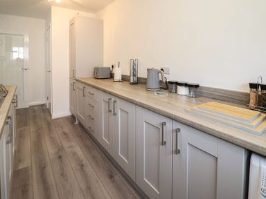 A kitchen with gray cabinets wooden countertop electric kettle toaster and cutting boards at The Old Coach House in Conwy