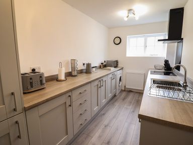 A kitchen with wooden countertops a sink toaster microwave and washing machine at The Old Coach House in Conwy