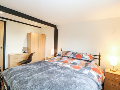 A bedroom with a bed and bedside tables with lamps and a wardrobe at Squirrel Lodge in North Walsham