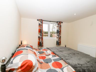 A bedroom with a bed covered with patterned bedding and matching curtains at Squirrel Lodge in North Walsham