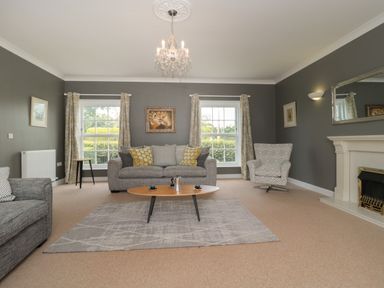 A living room with gray sofas a fireplace and a chandelier at Cherry Tree House in Highbridge