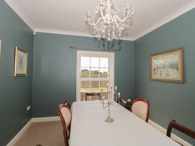A dining room with a large table covered with a white tablecloth and chairs around it at Cherry Tree House in Highbridge