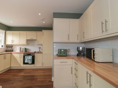 A kitchen with beige cabinets wooden countertops appliances including toaster microwave coffee machine and oven at Cherry Tree House in Highbridge