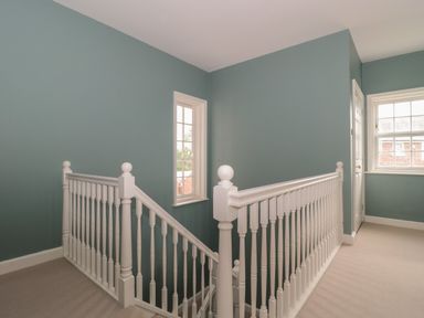 A staircase with white banisters and teal walls near windows at Cherry Tree House in Highbridge