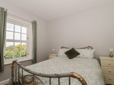 A bedroom with a bed and green curtains on the window at Cherry Tree House in Highbridge