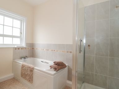 A bathroom with a bathtub next to a window and a shower with glass door at Cherry Tree House in Highbridge