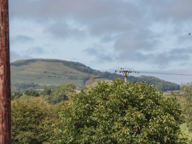 A landscape with green trees and hills under a cloudy sky at Cherry Tree House in Highbridge