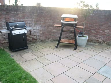 An outdoor patio area with a gas barbecue grill and a pizza oven on a stand next to a potted plant at Cherry Tree House in Highbridge