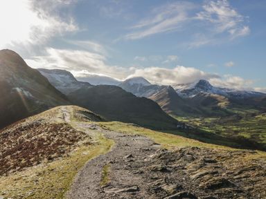 A mountain trail with snow capped peaks and a valley in the background at Beech Timber Lodge in Keswick