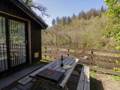An outdoor seating area with a table and wine bottle at Beech Timber Lodge in Keswick