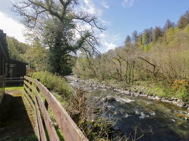 An outdoor area with a river and trees at Beech Timber Lodge in Keswick