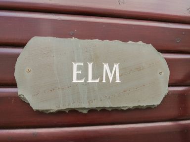 A stone plaque with the word ELM mounted on a wooden wall at Elm Lodge in Keswick