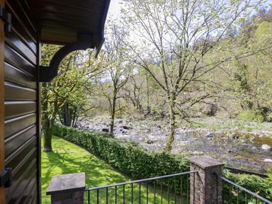 A view of a river and trees from a balcony at Elm Lodge in Keswick