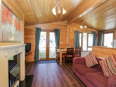 A living room with a sofa and dining table at Elm Lodge in Keswick