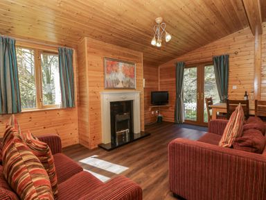 A living room with a sofa and fireplace at Elm Lodge in Keswick