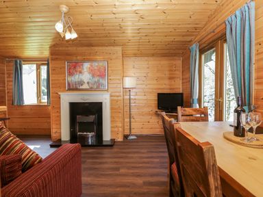 A living room with a sofa and dining table at Elm Lodge in Keswick