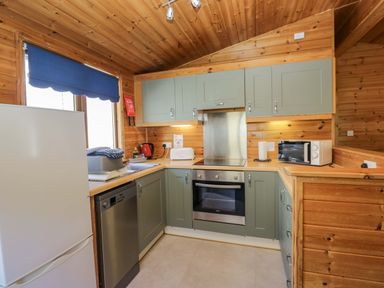 A kitchen with appliances and wooden accents at Elm Lodge in Keswick