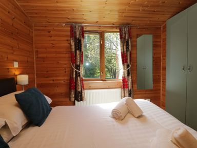 A bedroom with wood paneling and a window at Elm Lodge in Keswick
