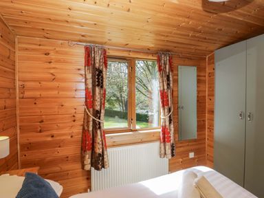 A bedroom with wooden walls and a window at Elm Lodge in Keswick