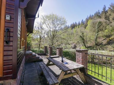 An outdoor seating area with a table and bench at Elm Lodge in Keswick