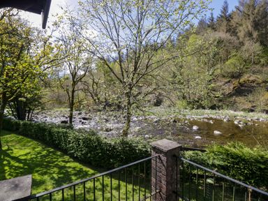 A view of a river with trees and grass at Elm Lodge in Keswick