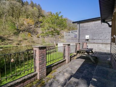 An outdoor area with a table and fenced grass area at Elm Lodge in Keswick
