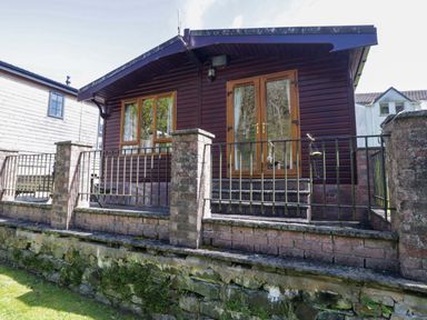 A cabin with a porch and railing at Elm Lodge in Keswick