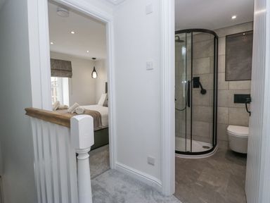 A hallway showing a bedroom with a bed and a bathroom with a shower at Riverside Cottage No 3 in Keswick