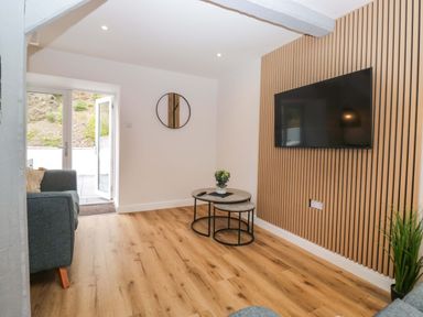 A living room with a television and a coffee table at Riverside Cottage No 5 in Keswick