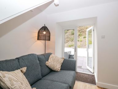 A living room with a sofa and a door leading outside at Riverside Cottage No 5 in Keswick