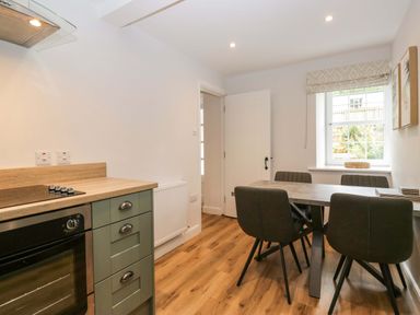 A kitchen with an oven and table at Riverside Cottage No 5 in Keswick