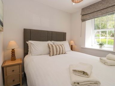 A bedroom with a bed and bedside table at Riverside Cottage No 5 in Keswick