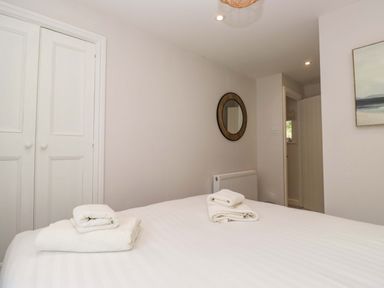 A bedroom with towels on the bed and a closet at Riverside Cottage No 5 in Keswick