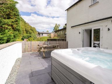 An outdoor area with a hot tub and seating at Riverside Cottage No 5 in Keswick