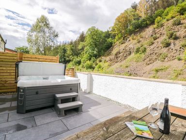 An outdoor area with a hot tub and table at Riverside Cottage No 5 in Keswick