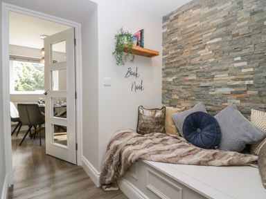 A book nook with cushions and a throw beside a door leading to a dining room at Garden Cottage No 1 in Keswick