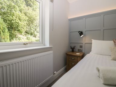 A bedroom with a bed bedside table window and radiator at Garden Cottage No 1 in Keswick