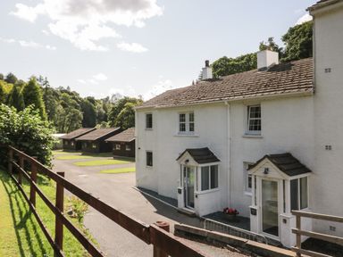 A row of white houses with small porches and a paved pathway beside a wooden fence at Garden Cottage No 1 in Keswick