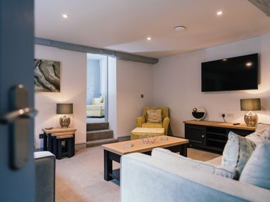 A living room with a sofa coffee table armchair and television at Greta House in Keswick