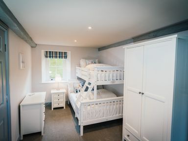 A bedroom with bunk beds a wardrobe a dresser and a bedside table with a lamp at Greta House in Keswick