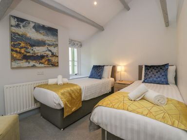 A bedroom with two single beds yellow blankets and blue pillows at Greta House in Keswick