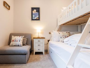 A bedroom with a gray couch a white nightstand and a white bunk bed at Briery House Keswick