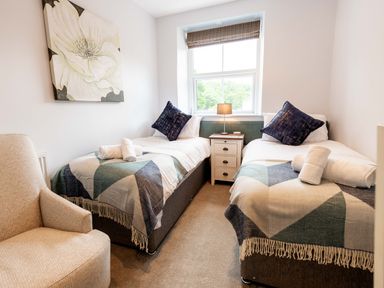 A bedroom with two single beds a nightstand and a chair at Briery House in Keswick