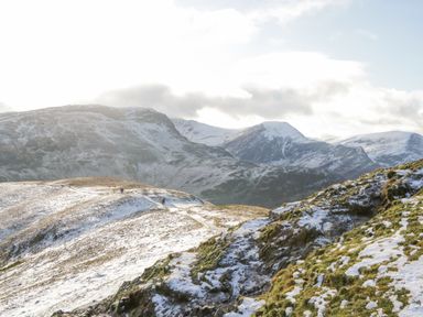 A snow-covered mountain landscape with a trail and two hikers at Briery House in Keswick