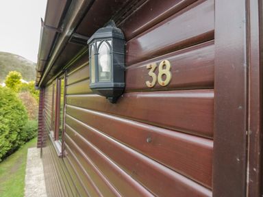 Outdoor wall of a brown wooden cabin with a black lantern and number 38 in Keswick