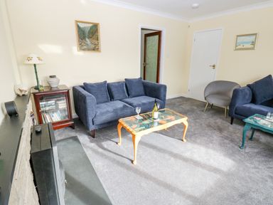 A living room with blue sofas a coffee table and a bookshelf at Pinegarth Catton near Allendale