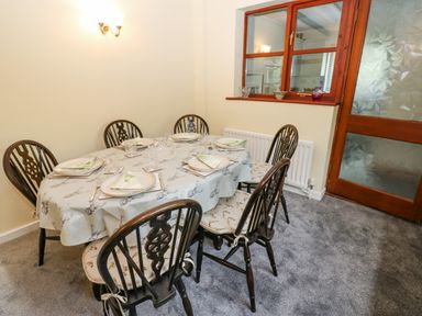 A dining room with a table set for six people chairs and a window at Pinegarth Catton near Allendale