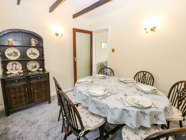 A dining room with a round table set for six and a wooden cabinet with decorative plates at Pinegarth Catton near Allendale