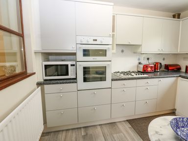 A kitchen with white cabinets a microwave built in oven gas stove red toaster and kettle Pinegarth Catton near Allendale